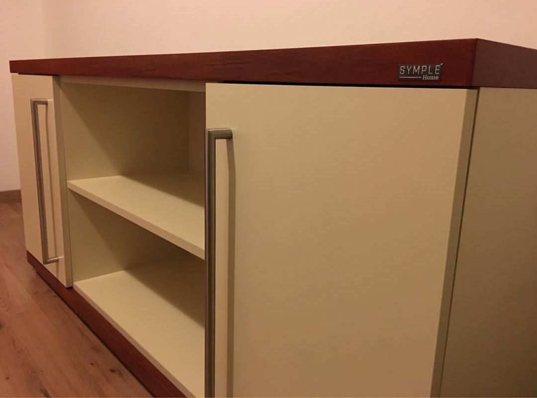 Armario color crema con dos puertas, dos estantes y tablero marrón oscuro. Tiradores plateados. Etiqueta