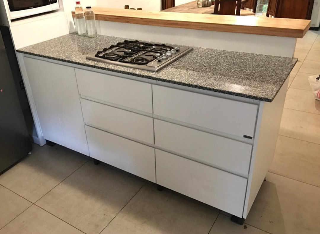 Isla de cocina blanca con estufa a gas, encimera de granito y cajones.