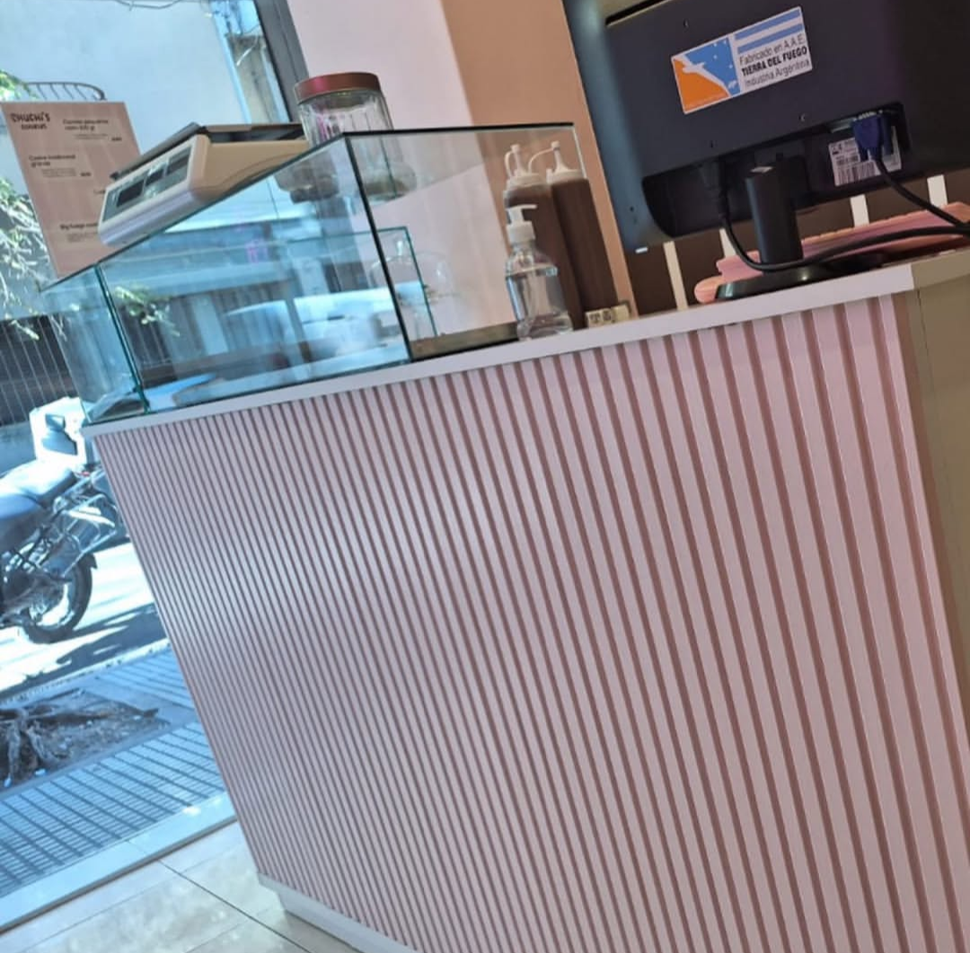 Mostrador de rayas rosas con vitrina de cristal, báscula y monitor de ordenador.