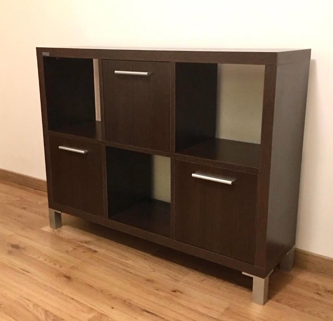 Estantería cúbica de color marrón oscuro con dos armarios y cuatro compartimentos abiertos sobre suelo de madera clara.