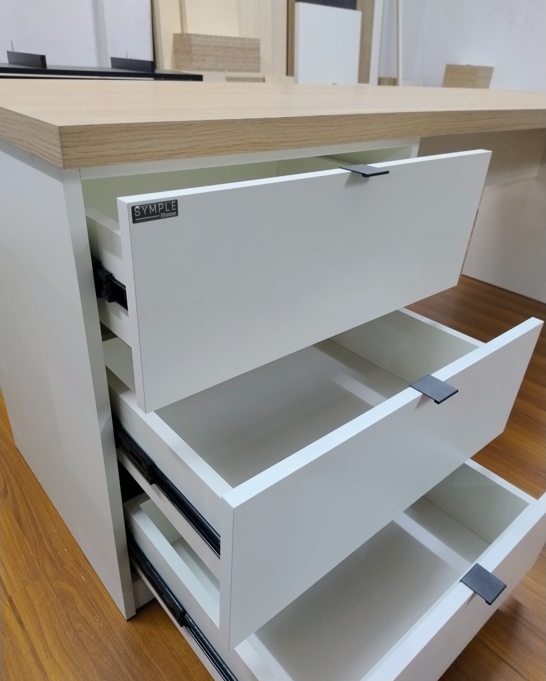 Escritorio blanco con tres cajones abiertos, encimera de madera clara.