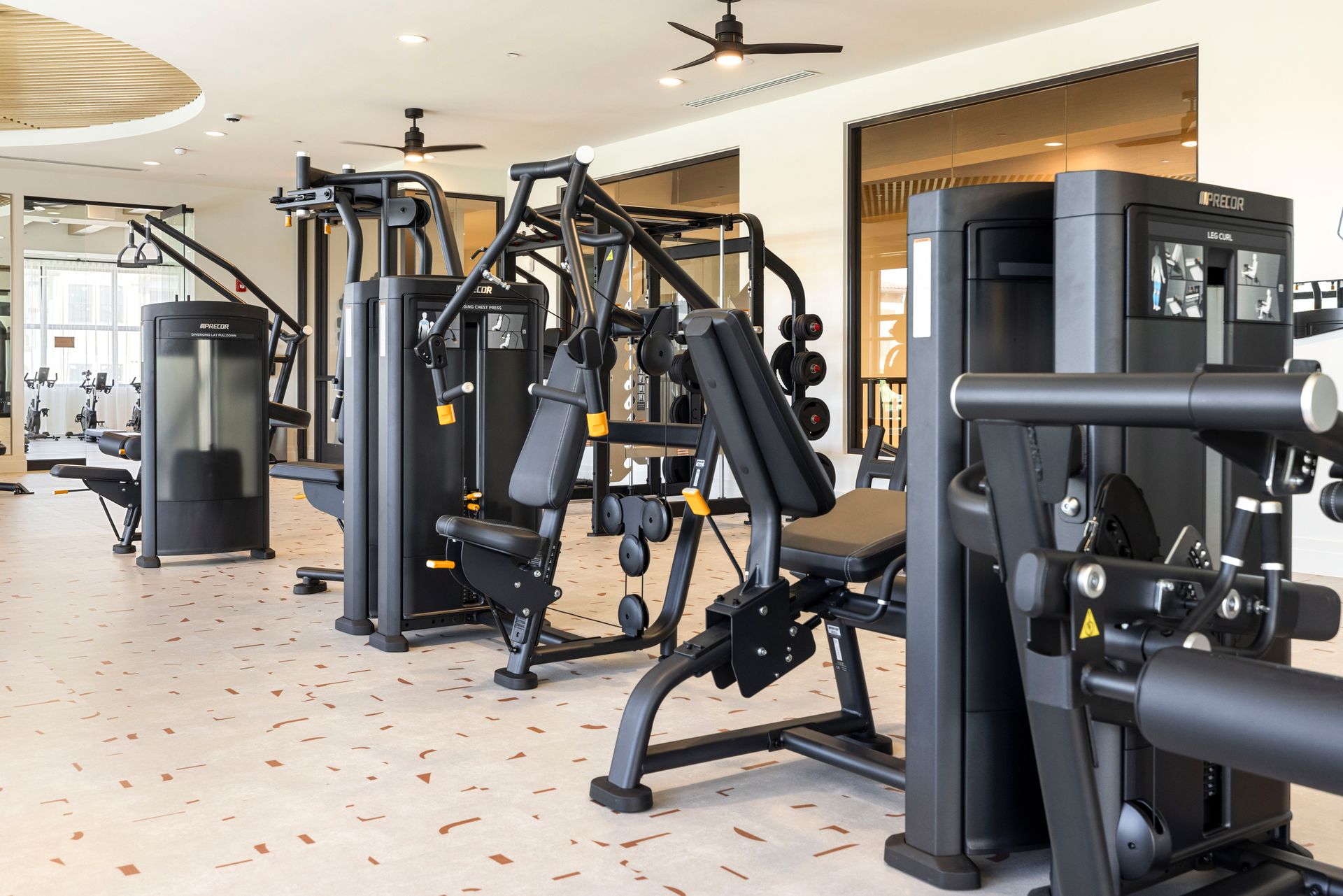 A gym filled with lots of exercise equipment and a ceiling fan at Corsa at Estero Crossing.