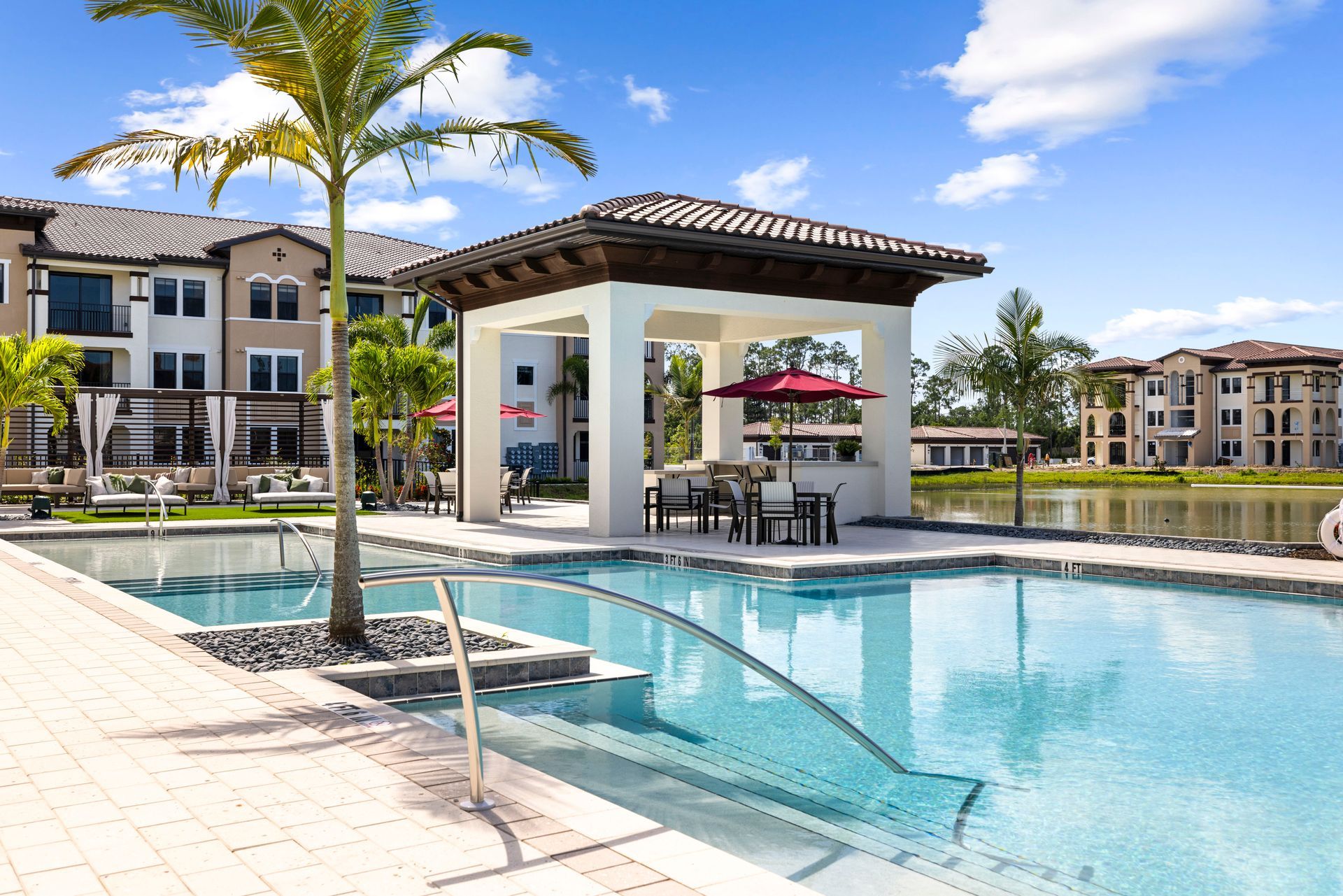 A large swimming pool surrounded by buildings and palm trees at Corsa at Estero Crossing.