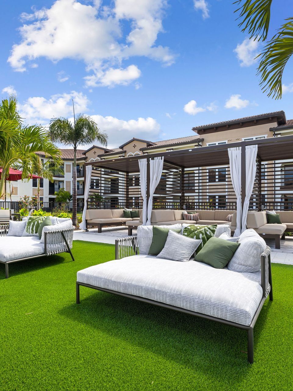 A couple of white couches sitting on top of a lush green lawn in front of a building at Corsa at Estero Crossing.
