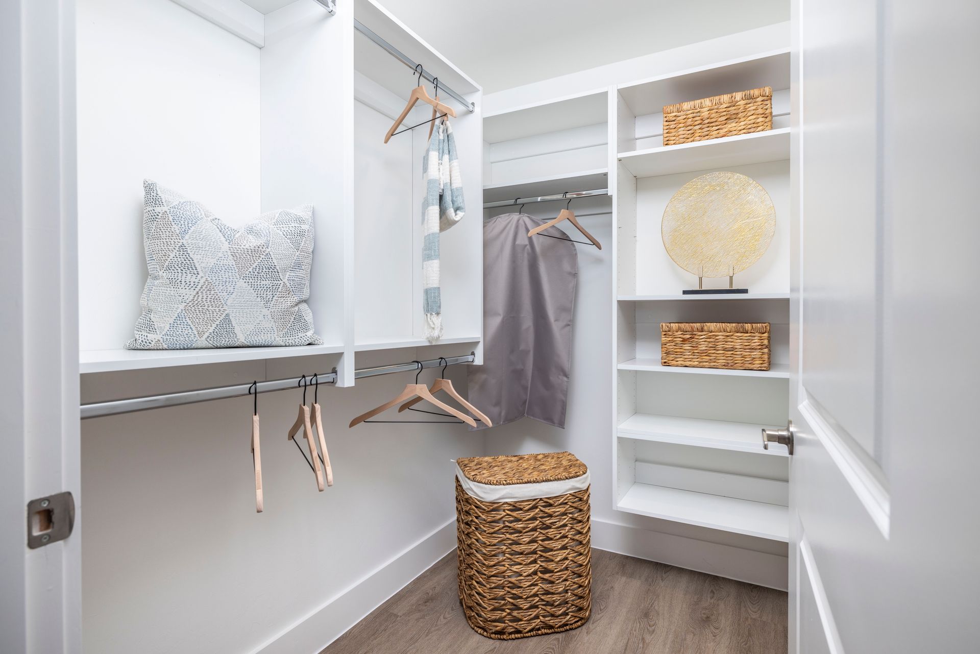 A walk in closet with clothes hanging on racks and a basket at Corsa at Estero Crossing.