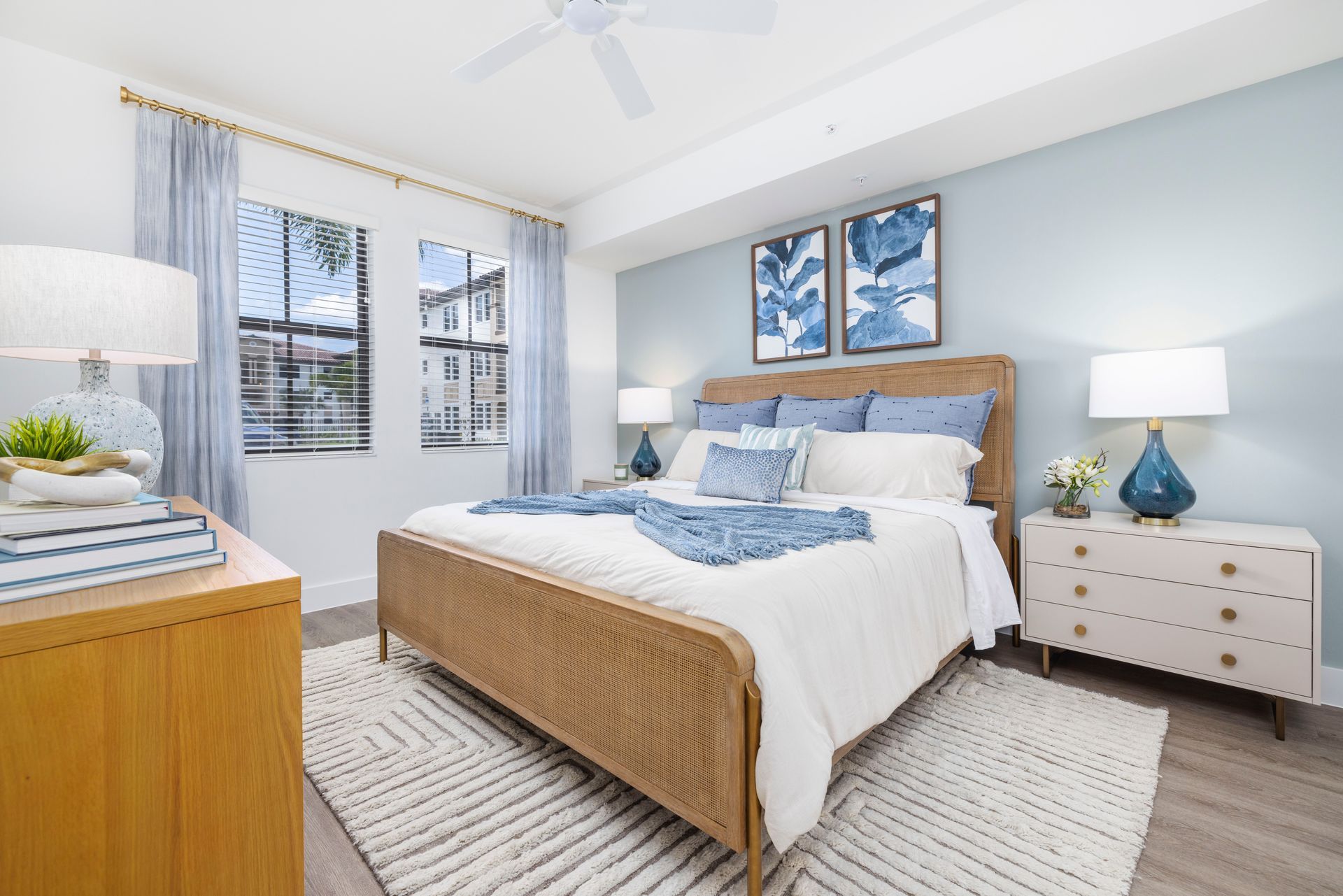 A bedroom with a king size bed , dresser , nightstand and ceiling fan at Corsa at Estero Crossing.