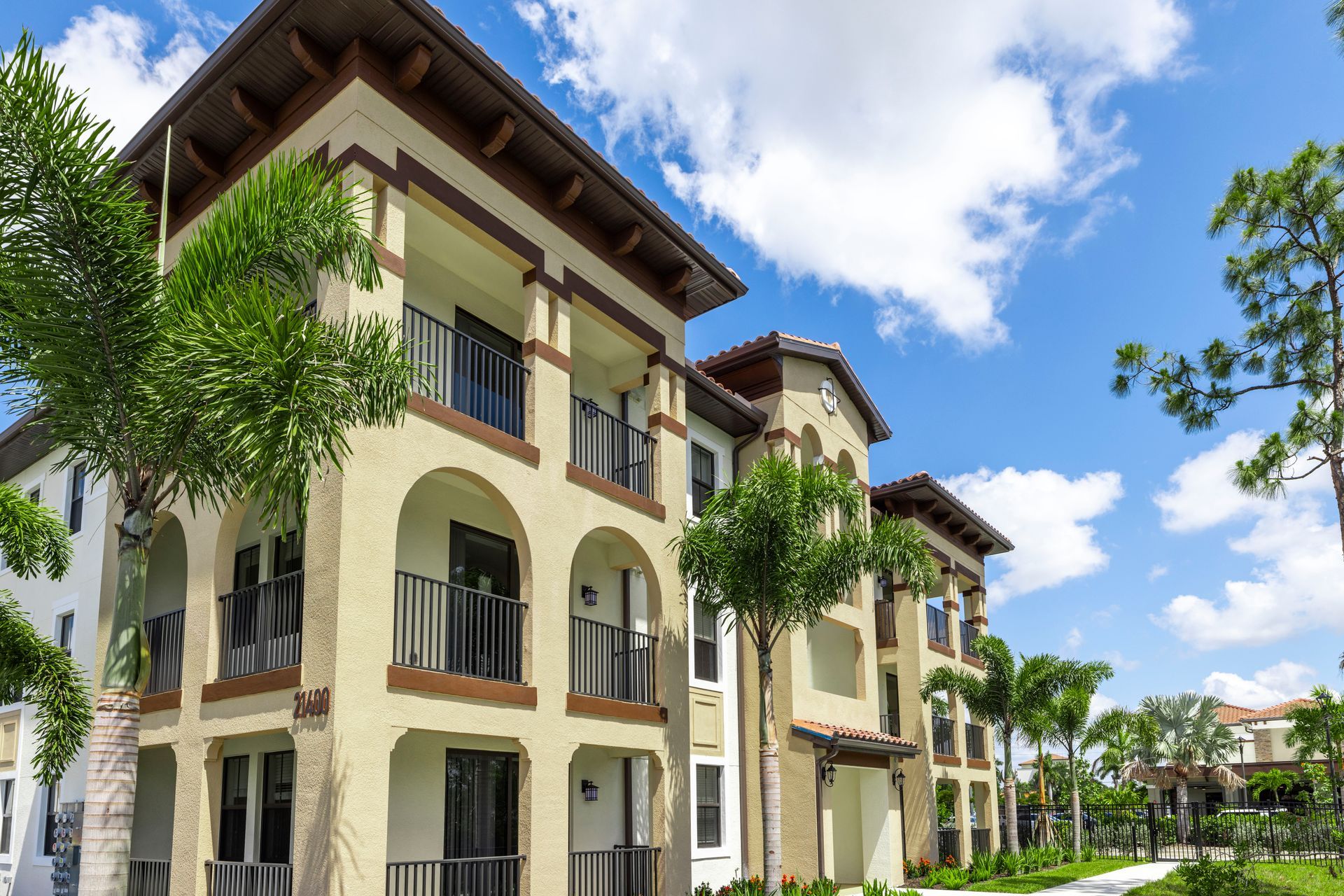 A large apartment building with palm trees in front of it on a sunny day at Corsa at Estero Crossing.