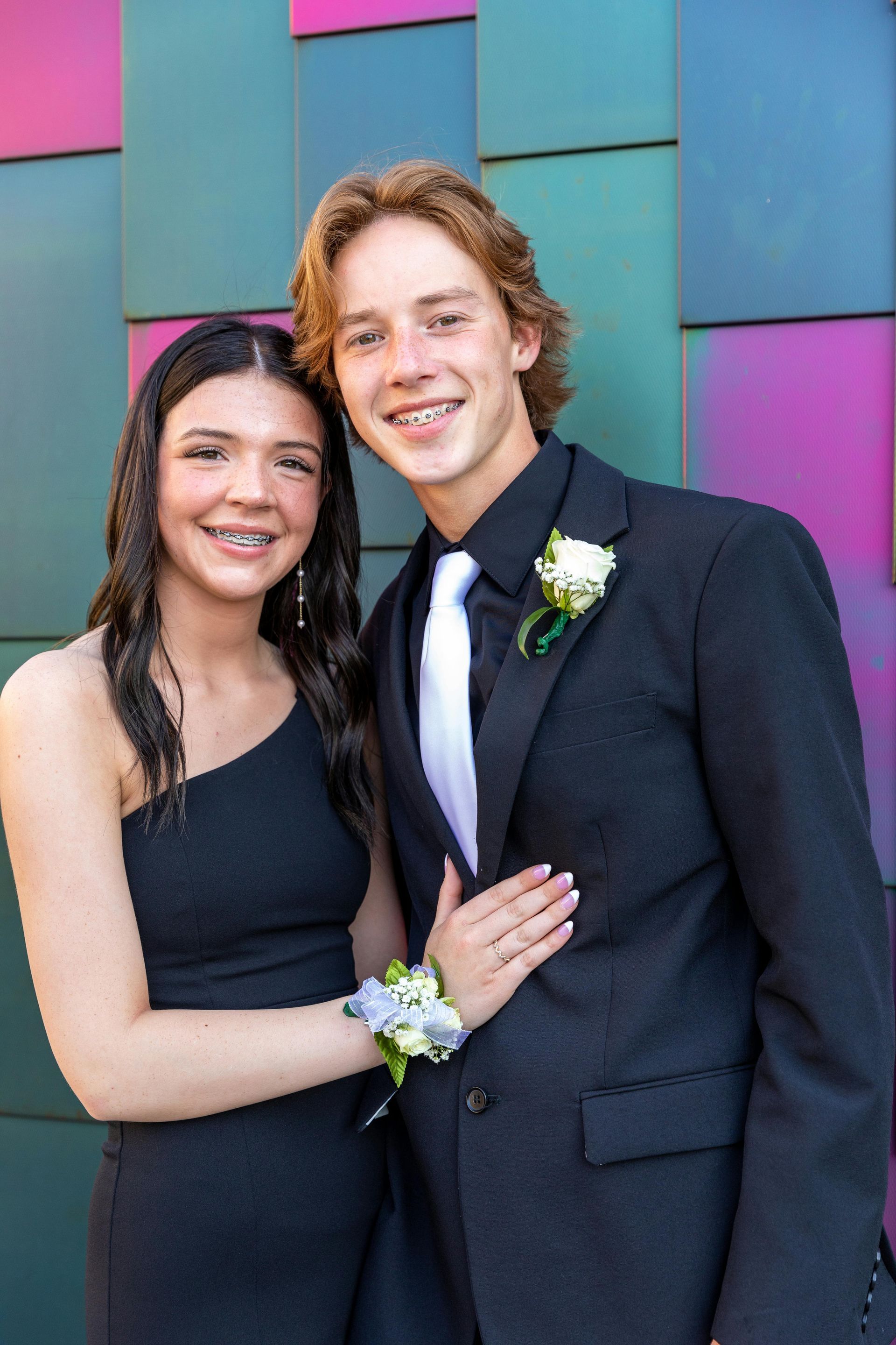 A man in a suit and tie is standing next to a woman in a black dress.