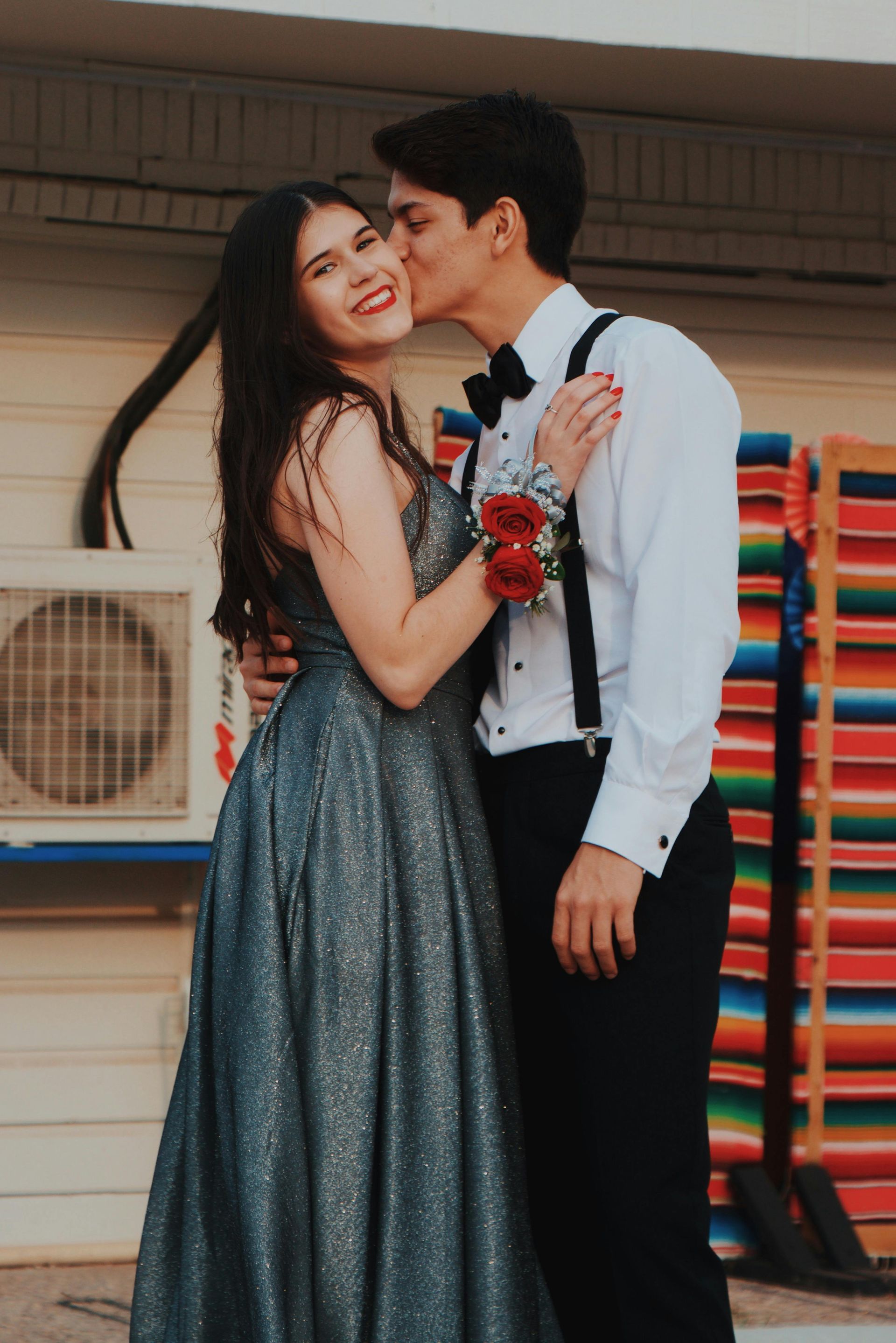A man kissing a woman on the cheek in front of a building
