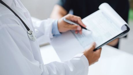 A doctor taking notes during an established patient office visit.