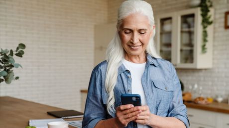An older woman checking her continuous glucose monitoring app on her phone.