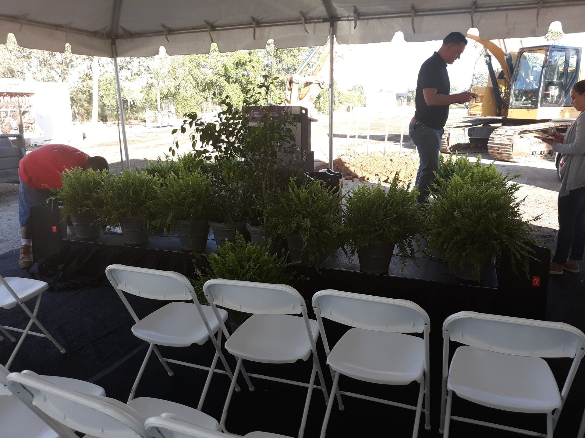 A row of white folding chairs under a tent