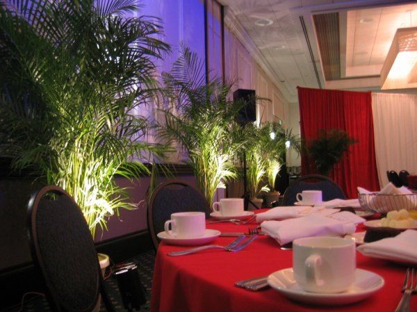 A table with a red table cloth and white cups and saucers on it