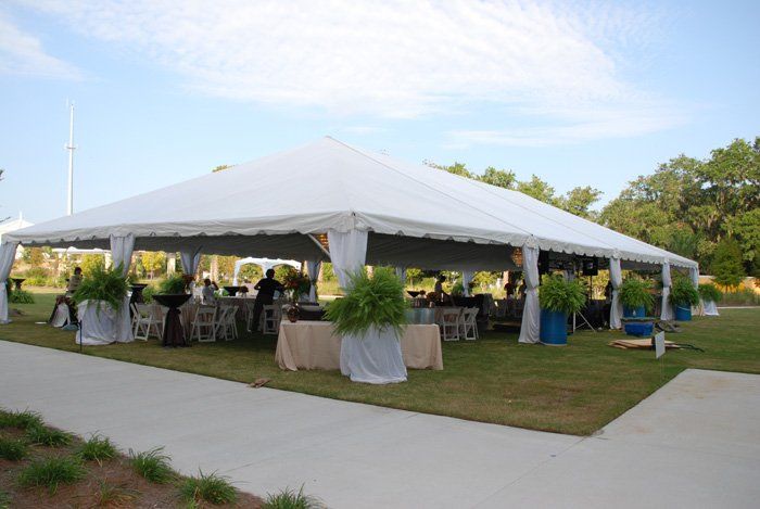 A large white tent is sitting on top of a lush green field.