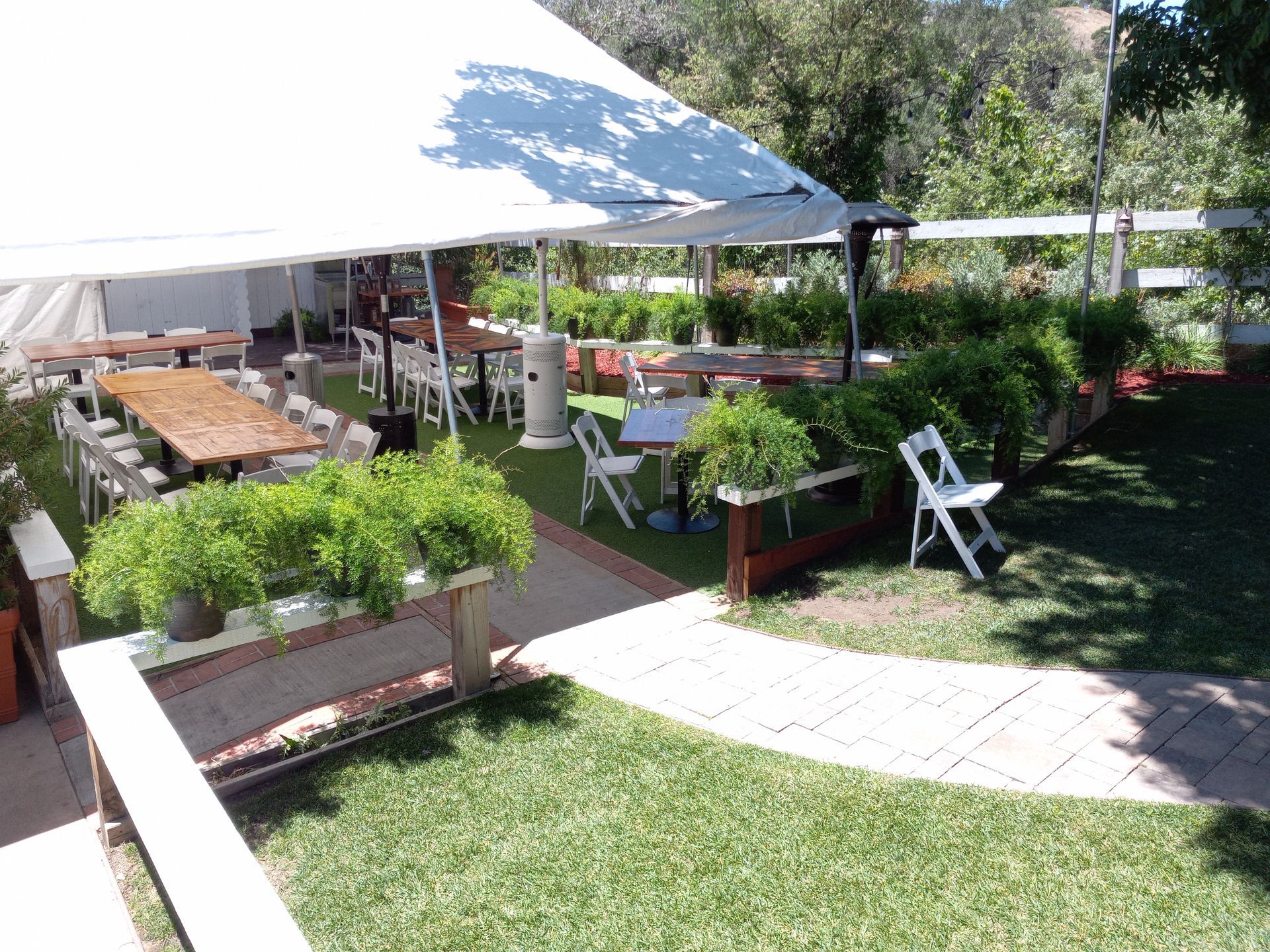 A large white tent is sitting in the middle of a lush green field.