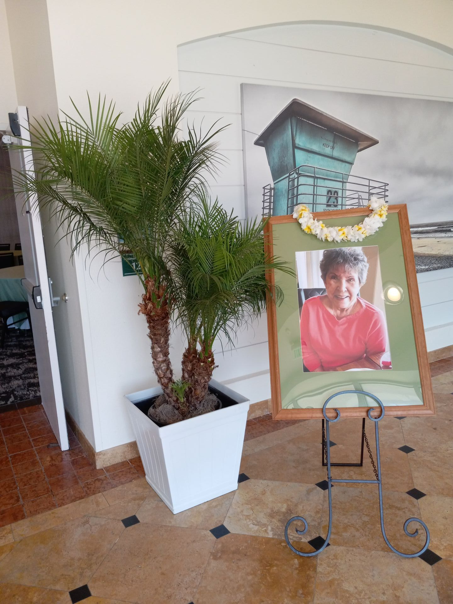A picture of a woman is on a stand next to a potted plant.
