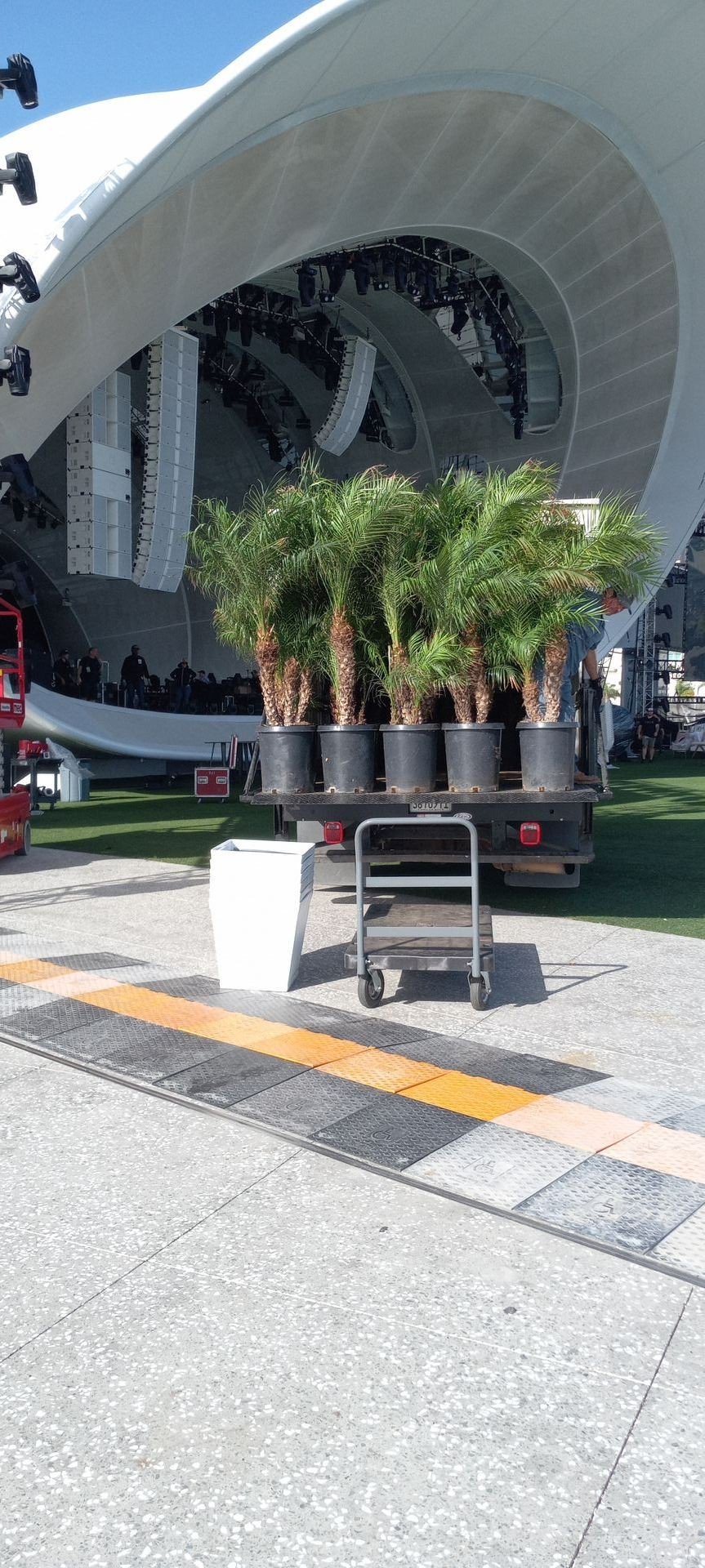 A bunch of potted plants are sitting on a cart in front of a building.