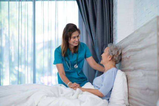 A Nurse Is Talking To An Elderly Woman Laying In A Hospital Bed - Morton Grove, IL - Orion Home Health (AKA Orion)