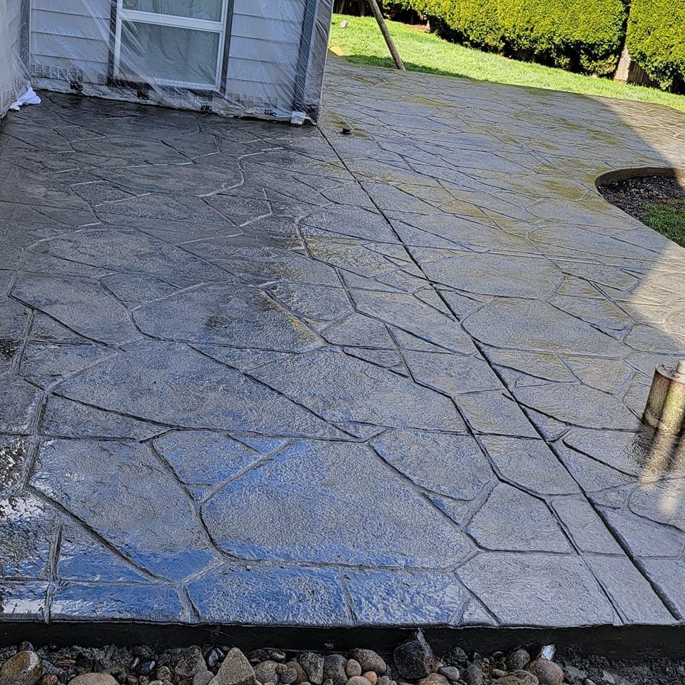 A concrete patio with a geometric pattern and a house in the background.