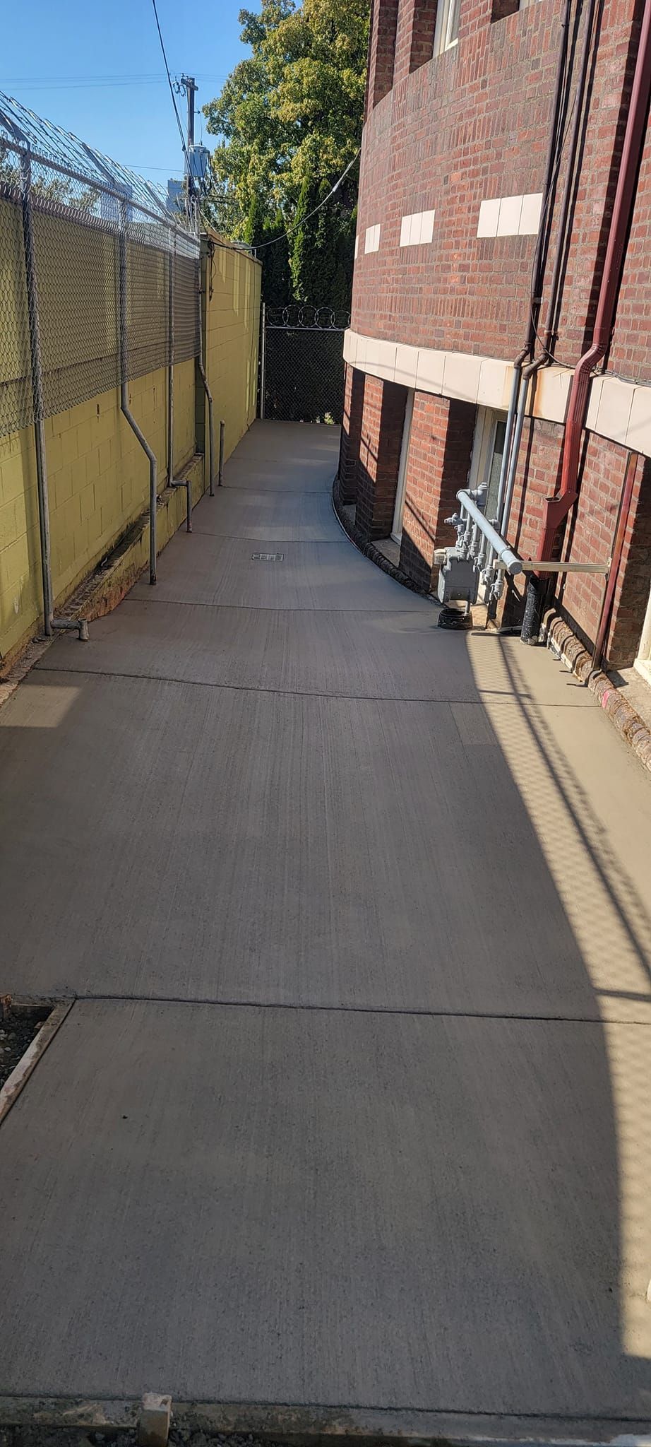 A narrow alleyway between two buildings with a barbed wire fence.