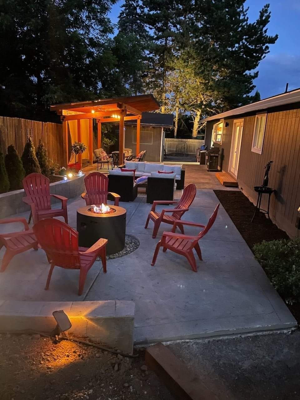 A patio with red chairs and a fire pit at night