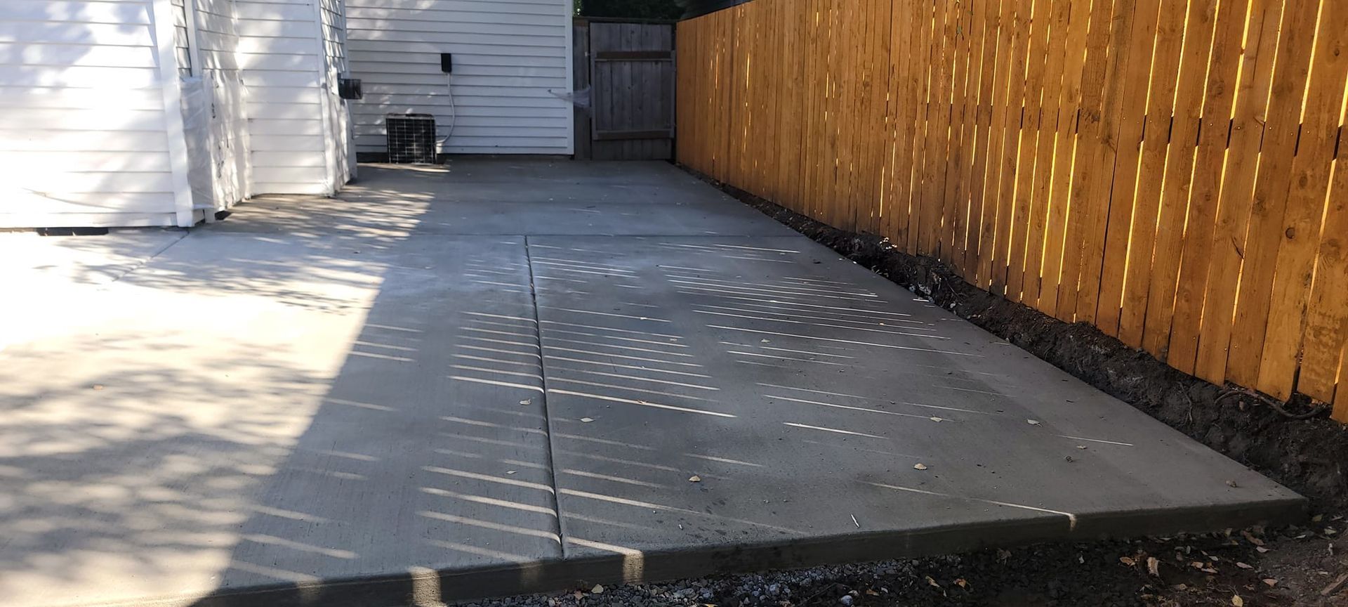 A concrete driveway with a wooden fence in the background.