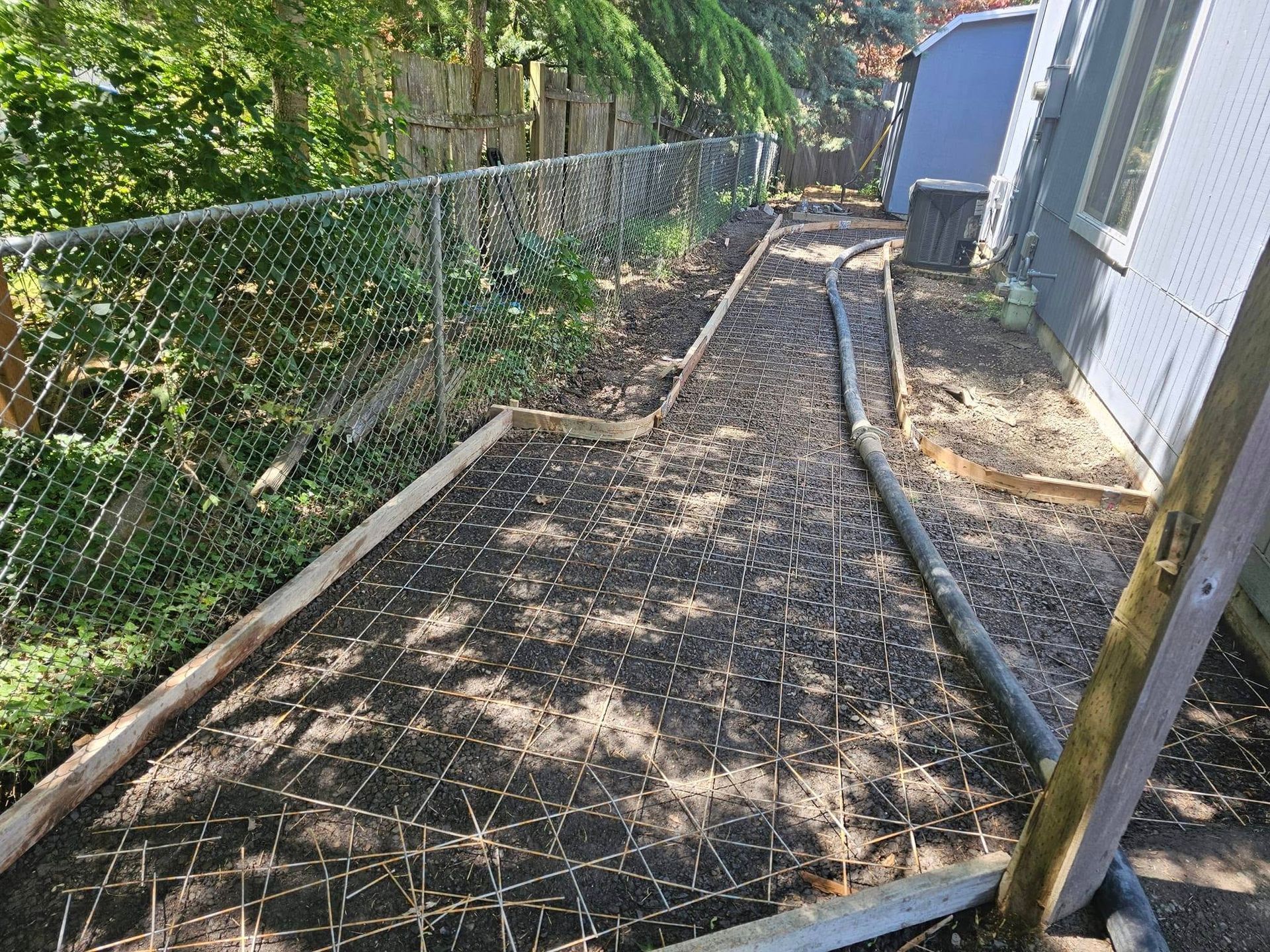 A concrete walkway is being built in the backyard of a house.