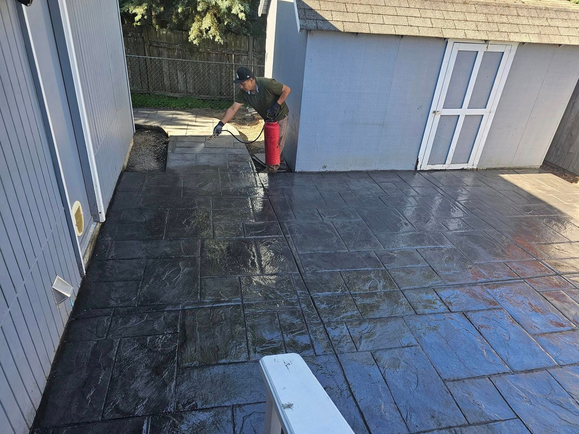 A man is standing on a concrete patio in front of a shed.