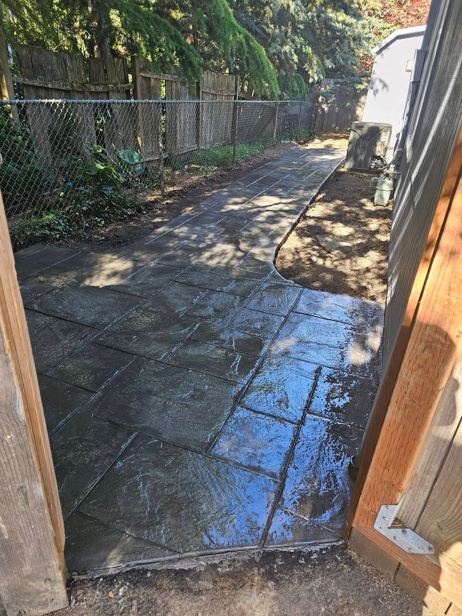 A concrete walkway is being built in a backyard.