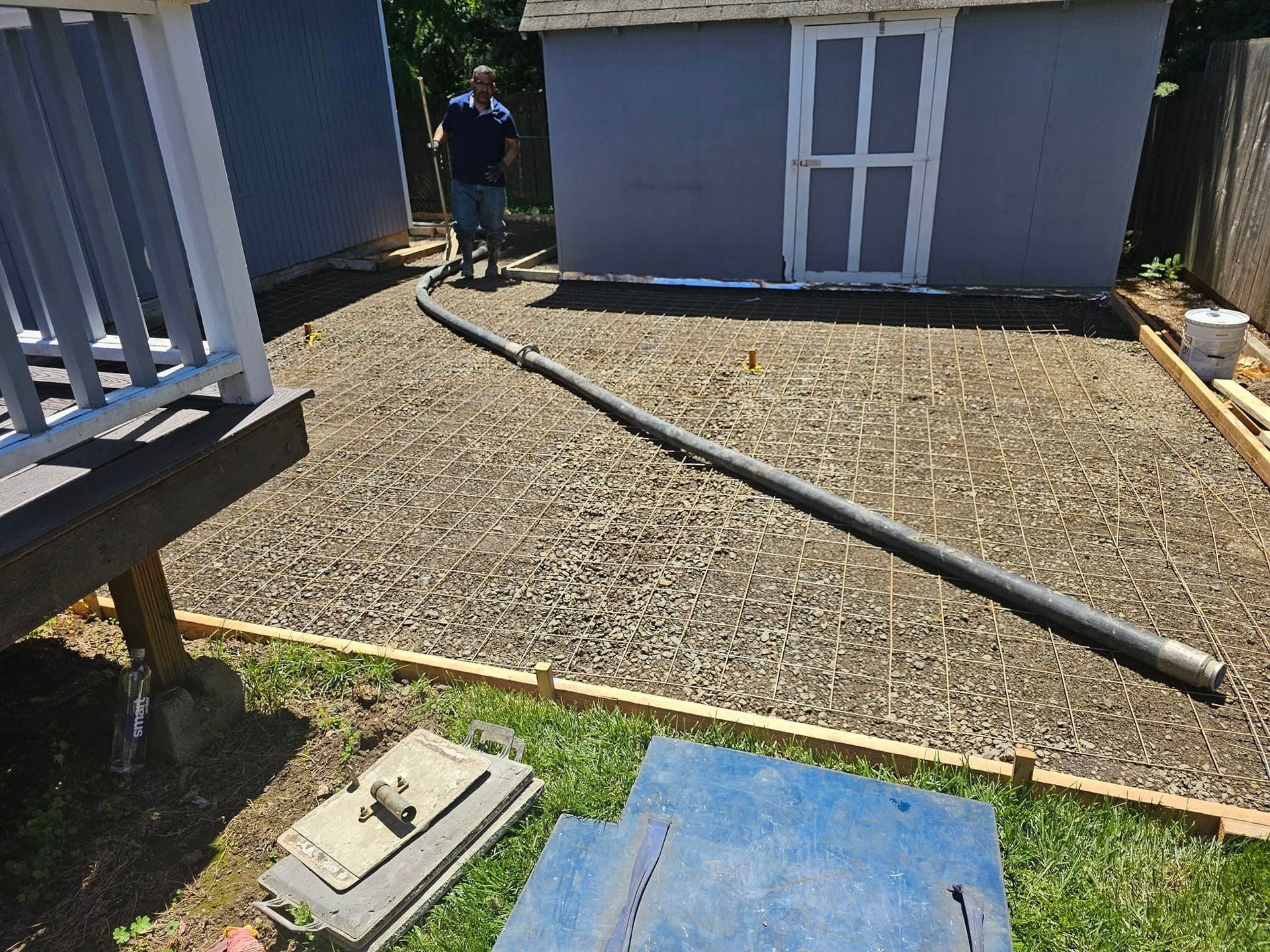 A man is standing in front of a shed in a backyard.
