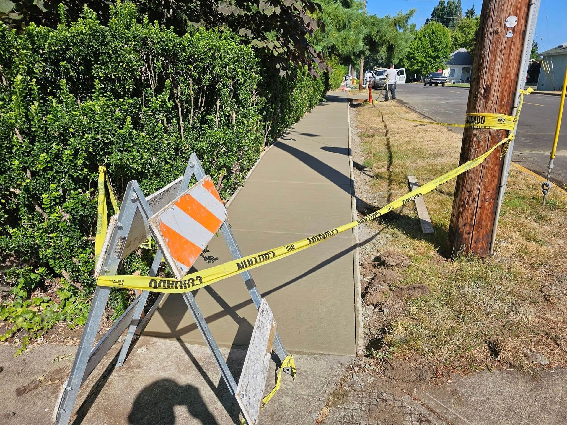 A concrete sidewalk is being worked on by a construction crew.