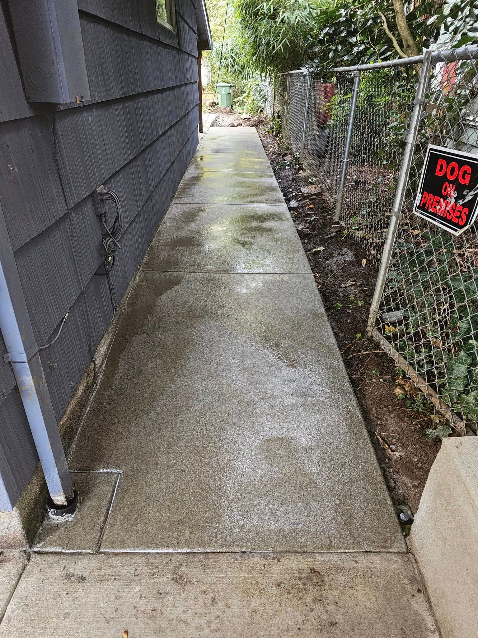 A sidewalk leading to a house with a chain link fence.