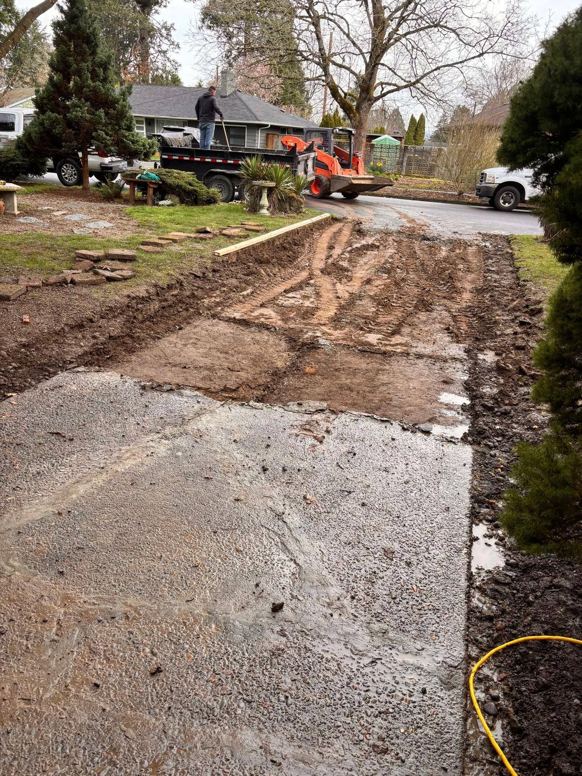 A man is standing on a trailer next to a dirt road.