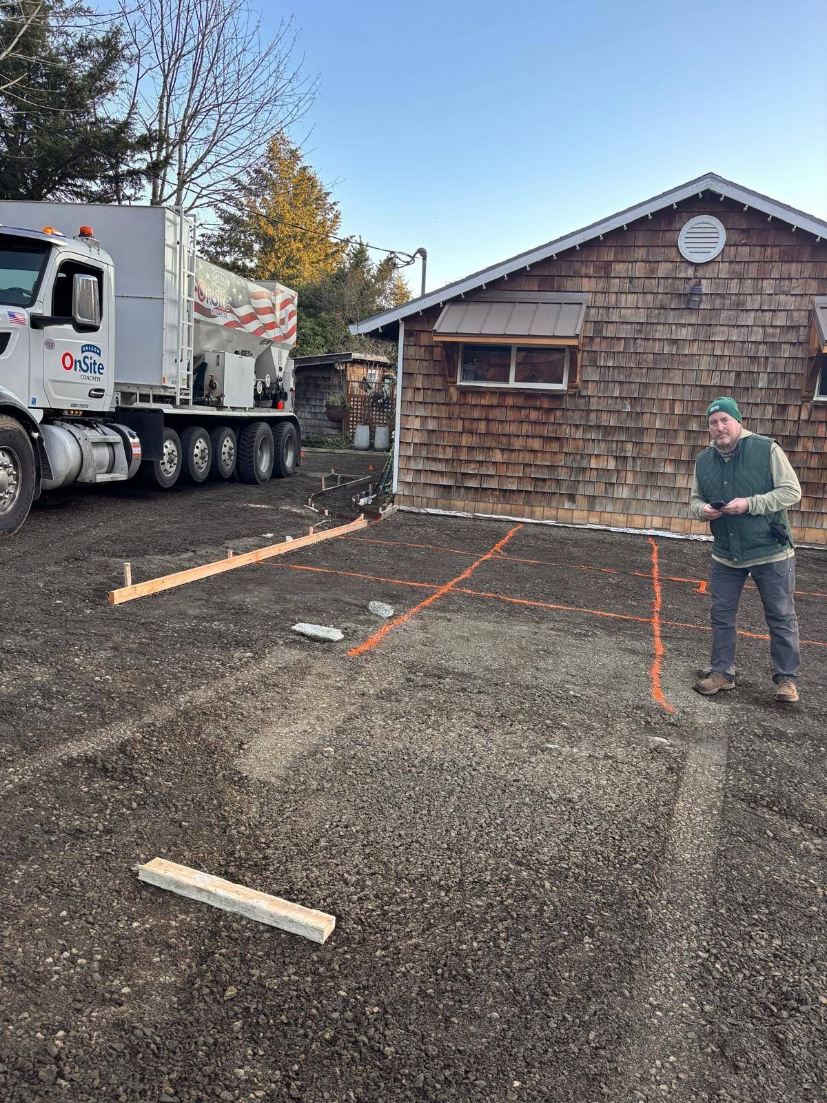 A man is standing in front of a truck in a parking lot.