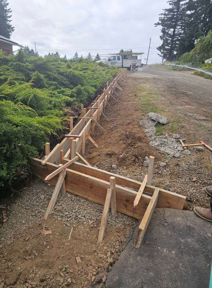 A wooden fence is being built on the side of a dirt road.