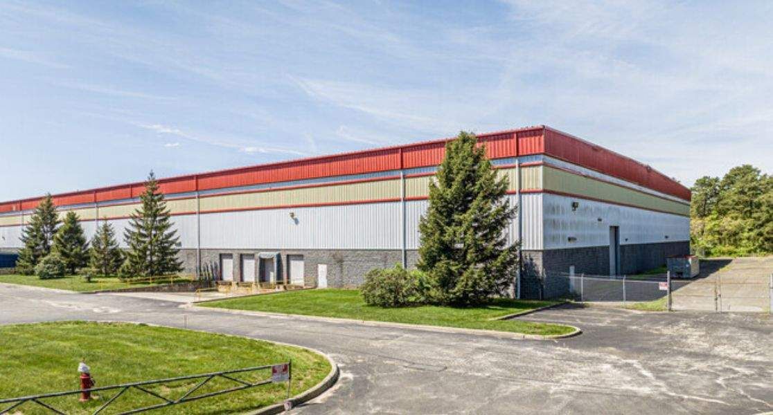 Modern two-story building with cars parked in front and American flag.