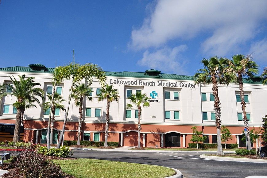 Modern office building with blue-tinted windows, a grassy lawn, and mountains in the background. 