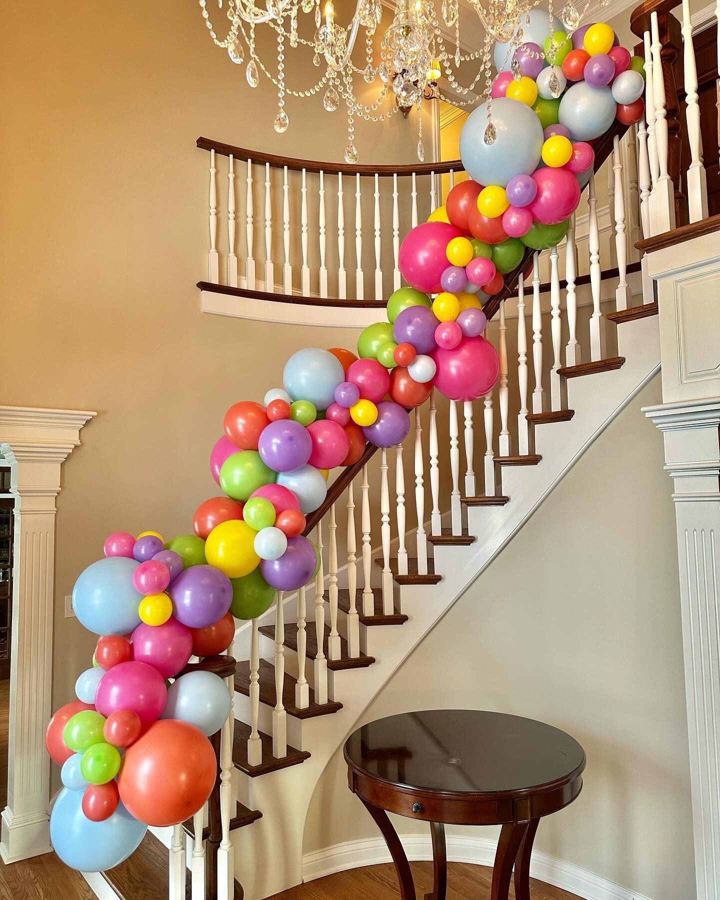 A staircase decorated with colorful balloons and a chandelier