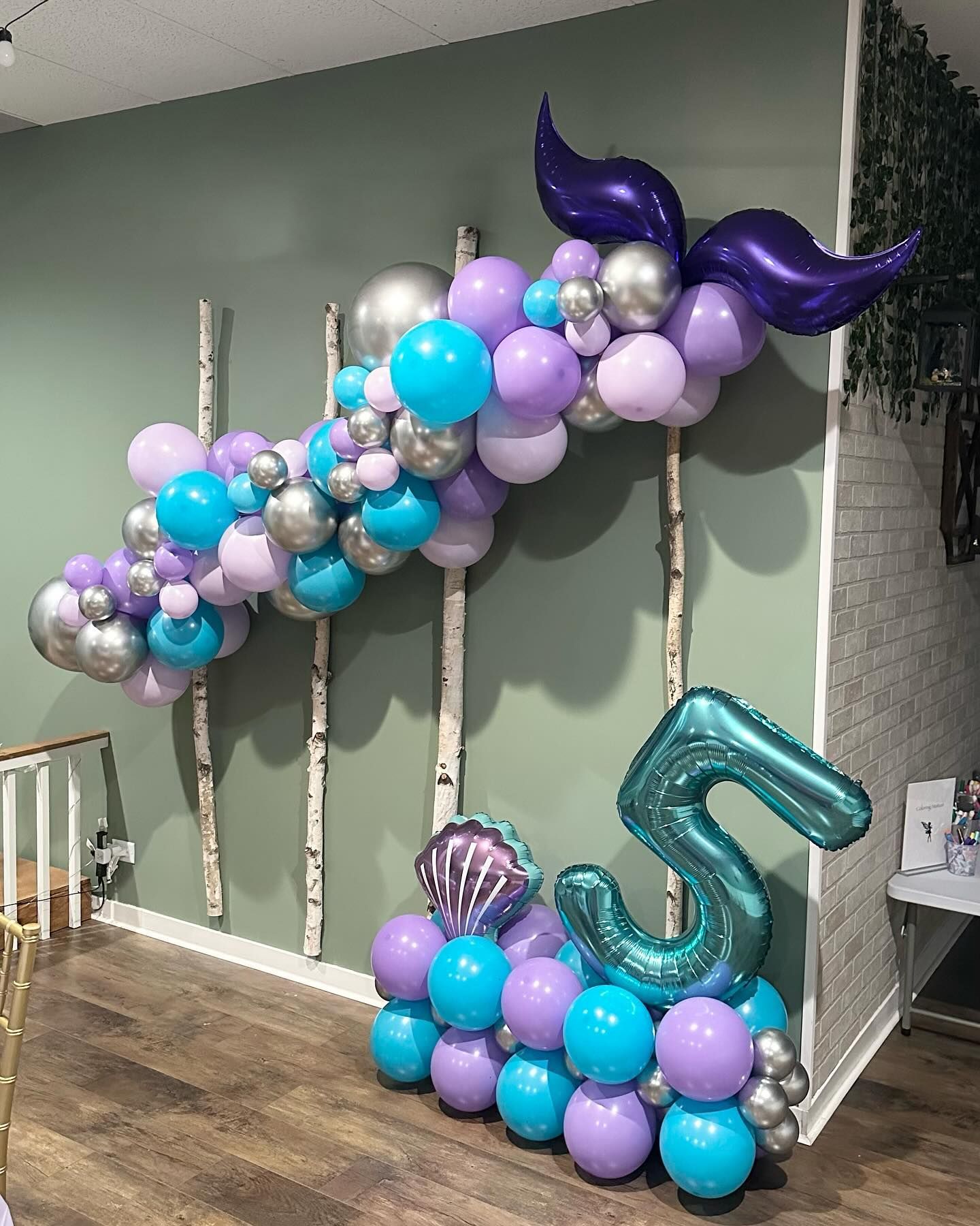 A bunch of balloons are sitting on a wooden floor in a room.