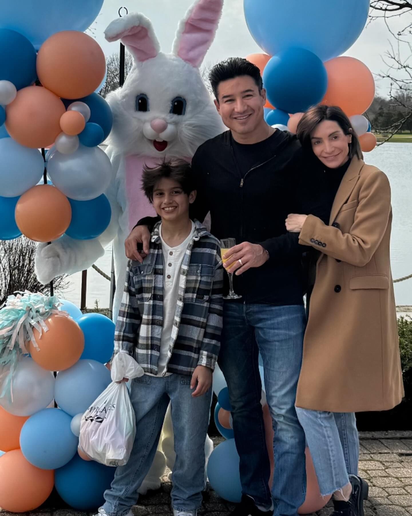 A family is posing for a picture in front of a bunny mascot and balloons.