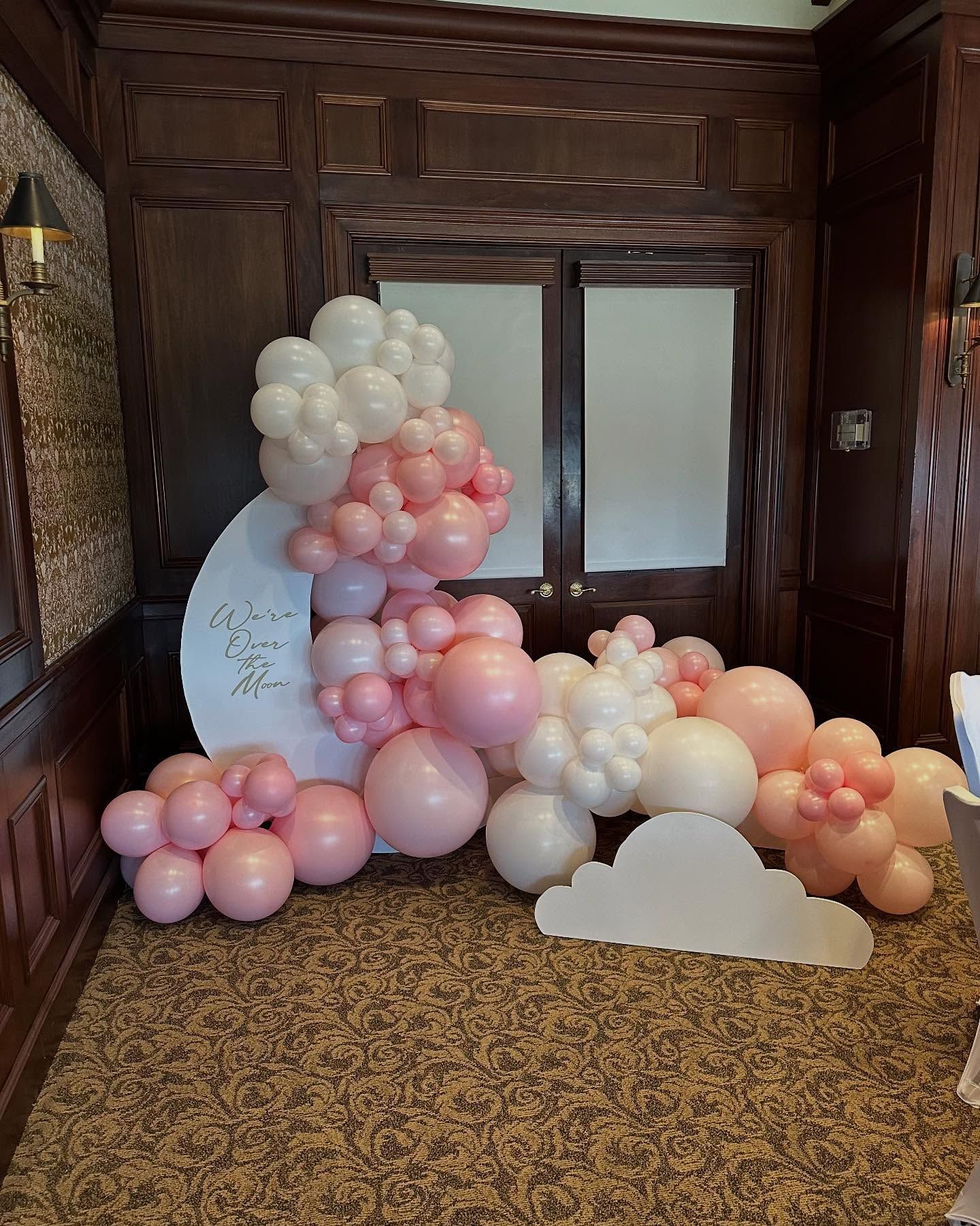 A room filled with pink and white balloons and a cloud.
