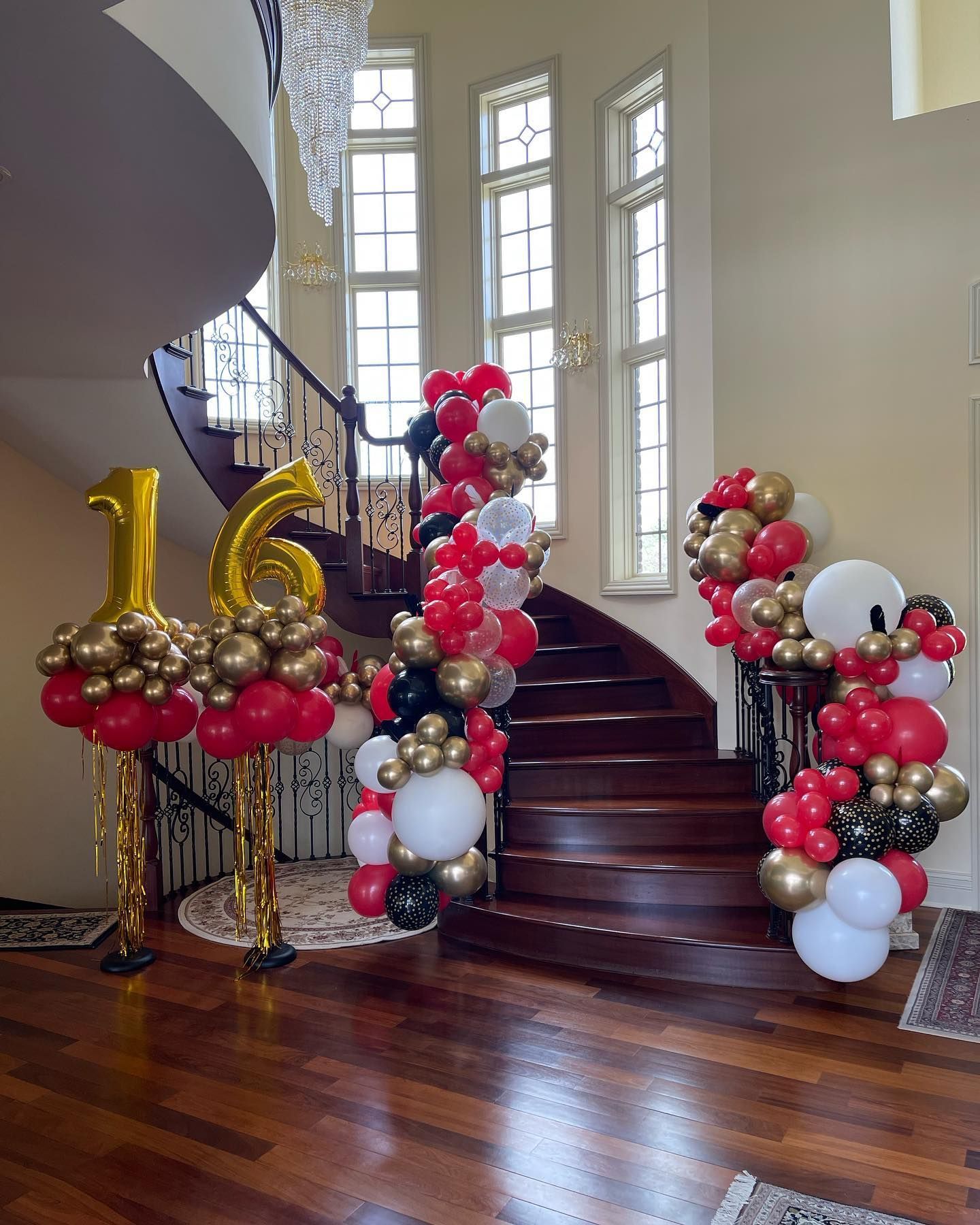 A staircase decorated with red , gold and white balloons for a 16th birthday.