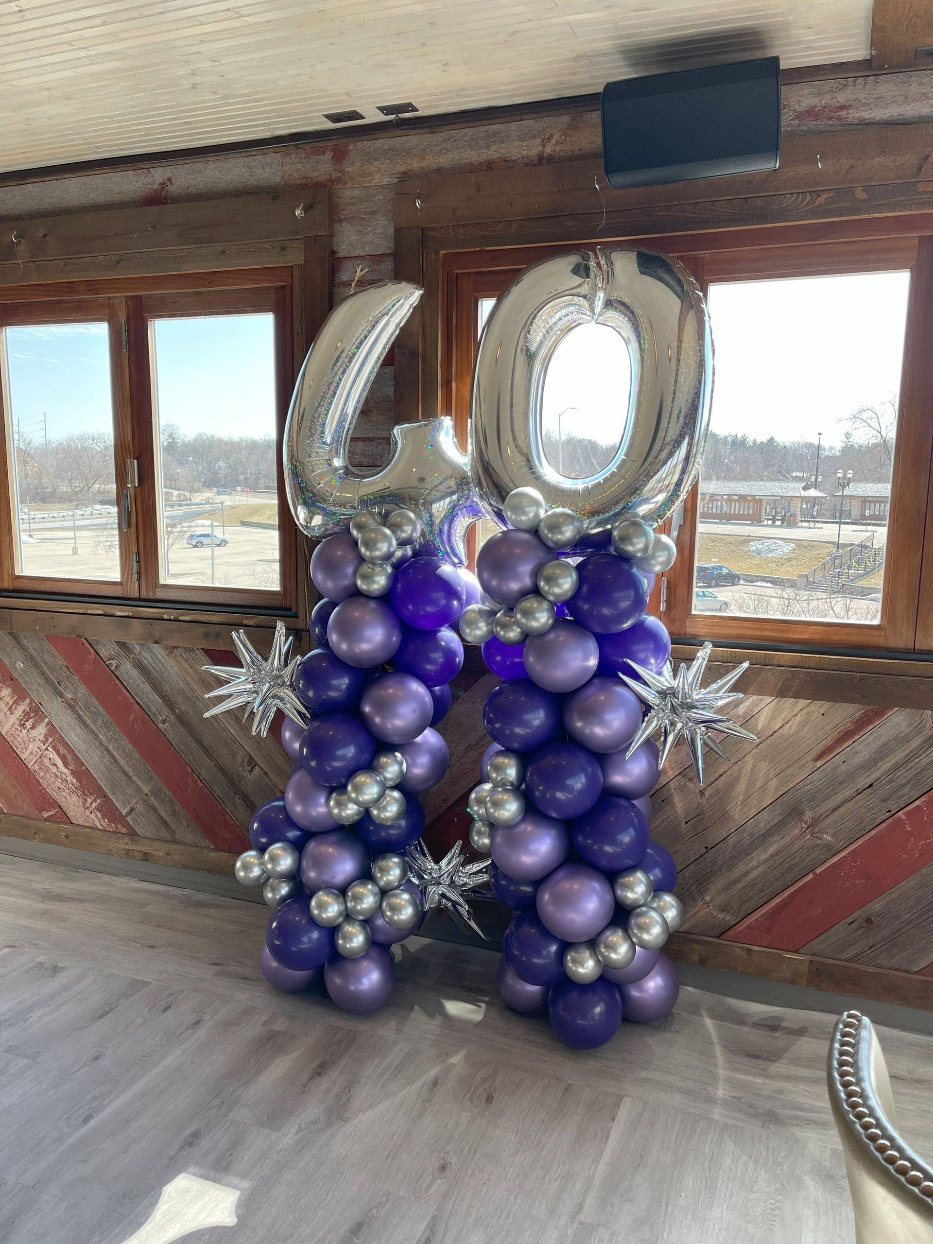 Purple and silver balloons are stacked on top of each other in a room.