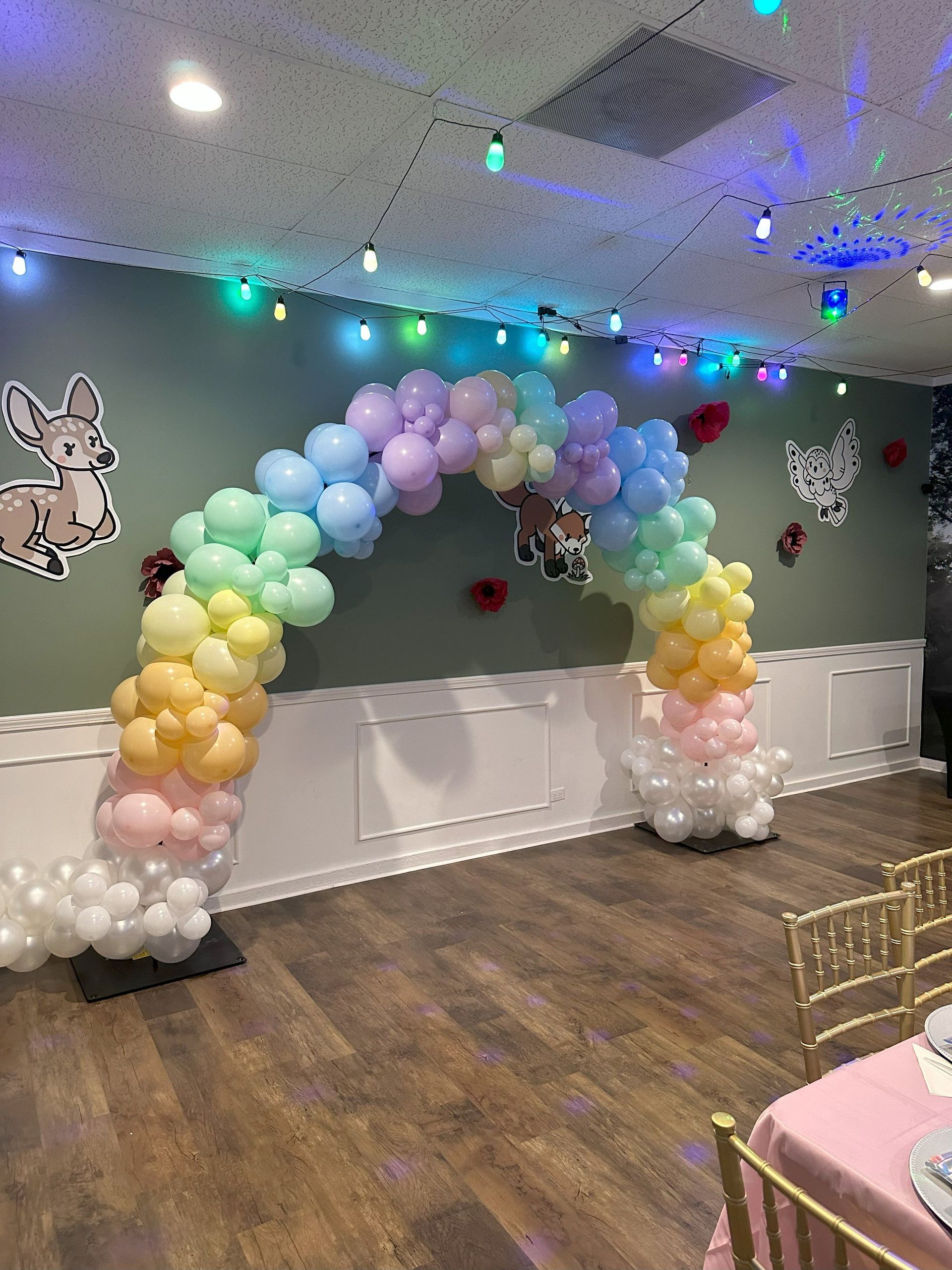 A room decorated with balloons and a rainbow arch.