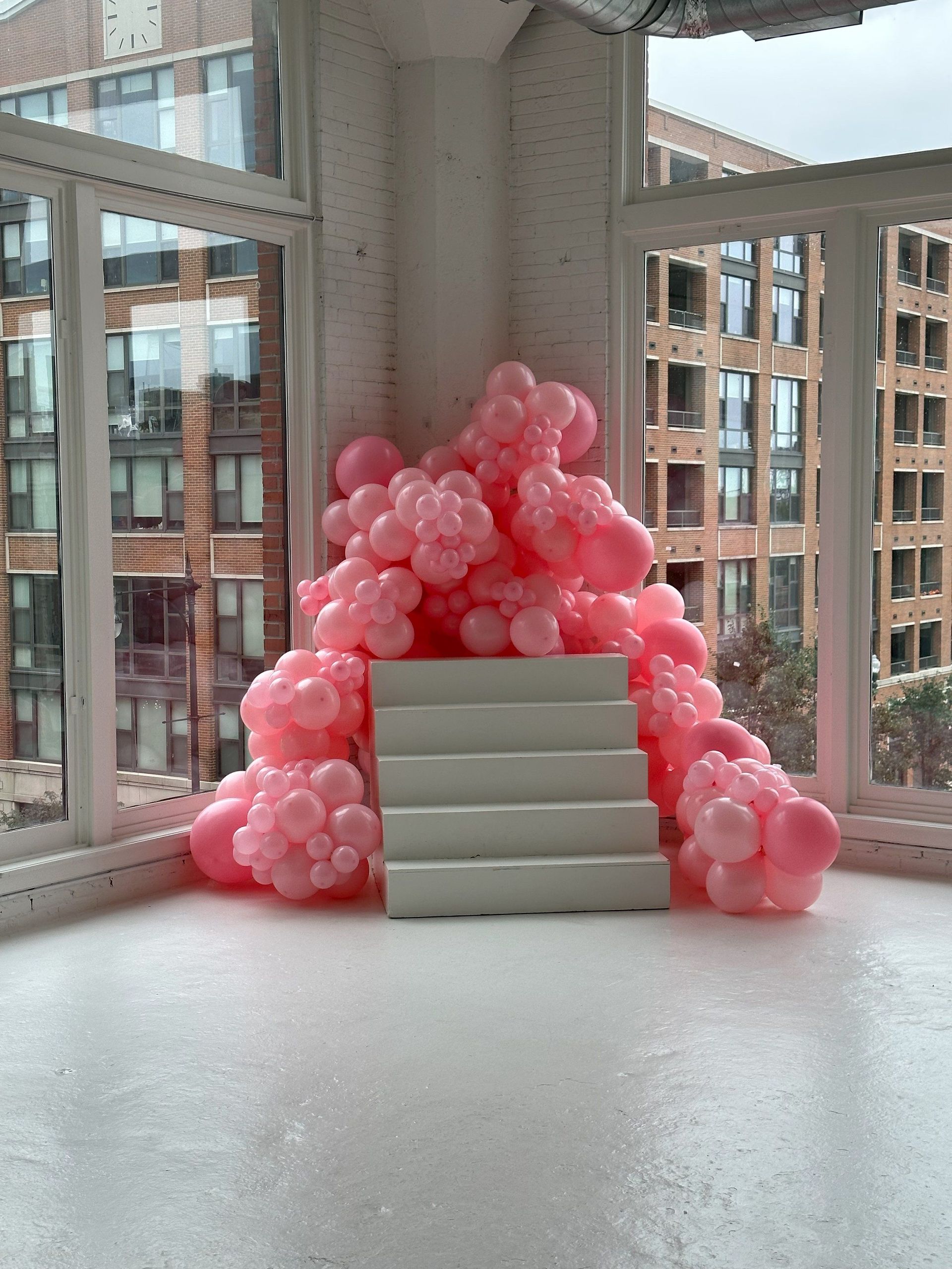 A pile of pink balloons sitting on top of white stairs
