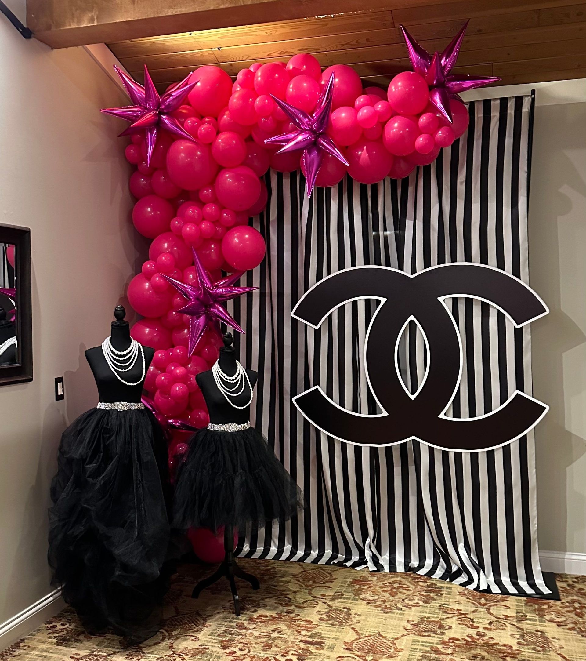 A room decorated with pink balloons and a chanel logo