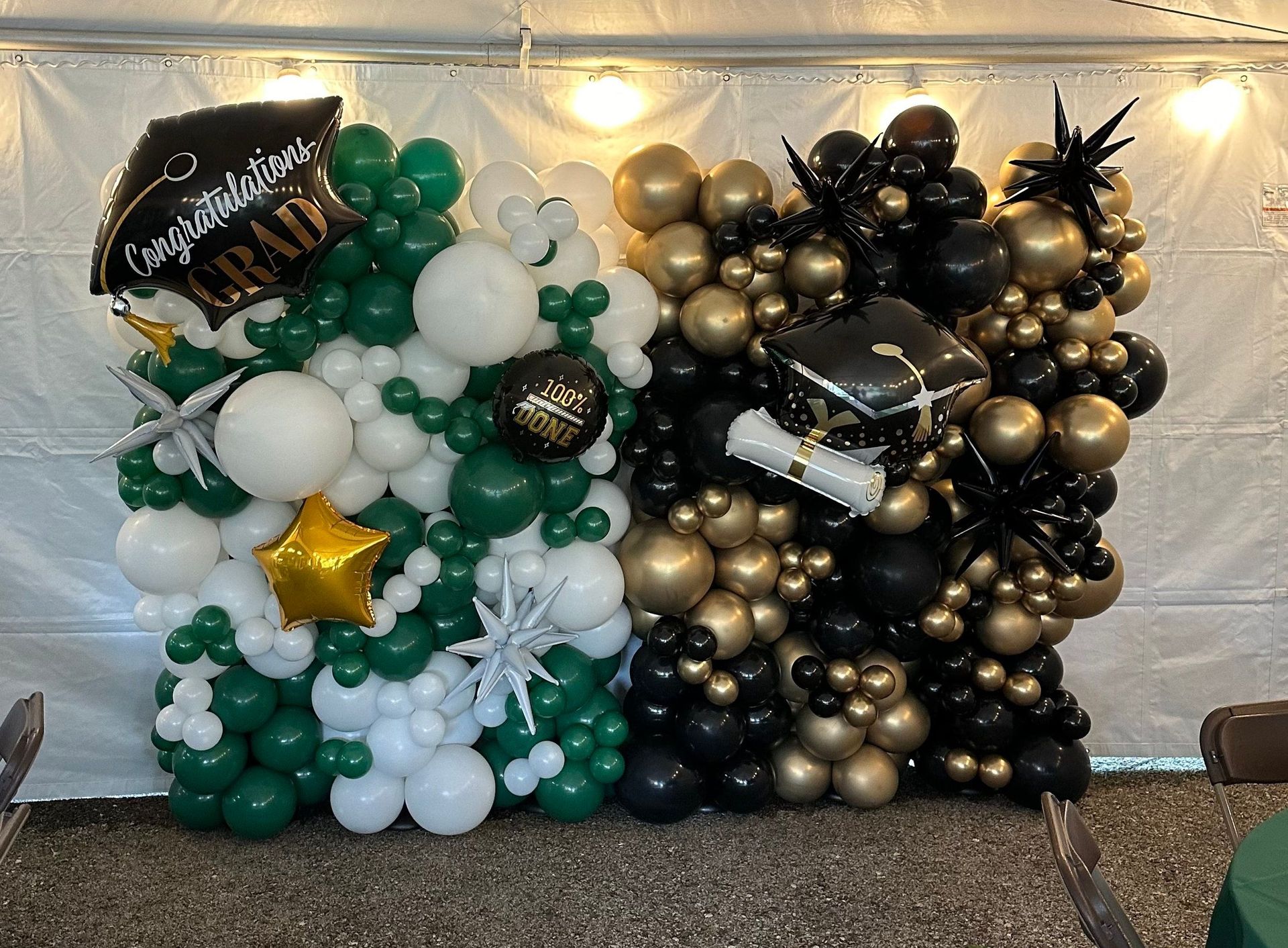 A wall of balloons with a graduation cap and diploma on it.