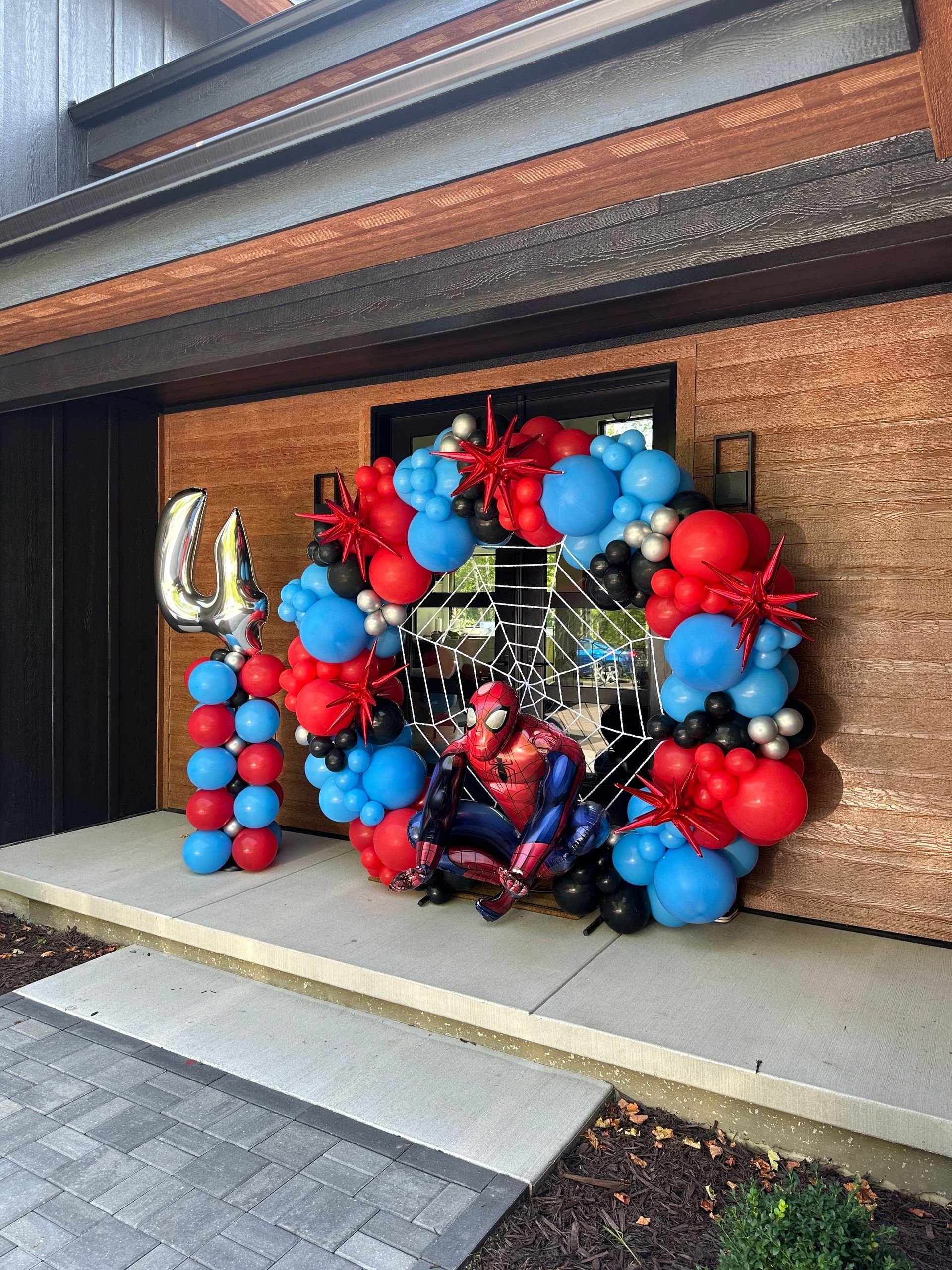 A spiderman balloon arch is sitting in front of a brick building.