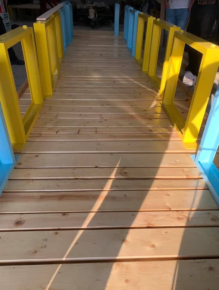 Wooden walkway with yellow and blue painted supports.