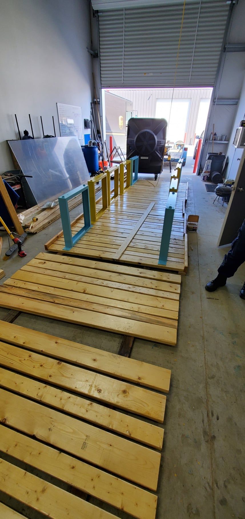 Wooden pallets and structures inside a garage-like space, with a roller door open in the background.